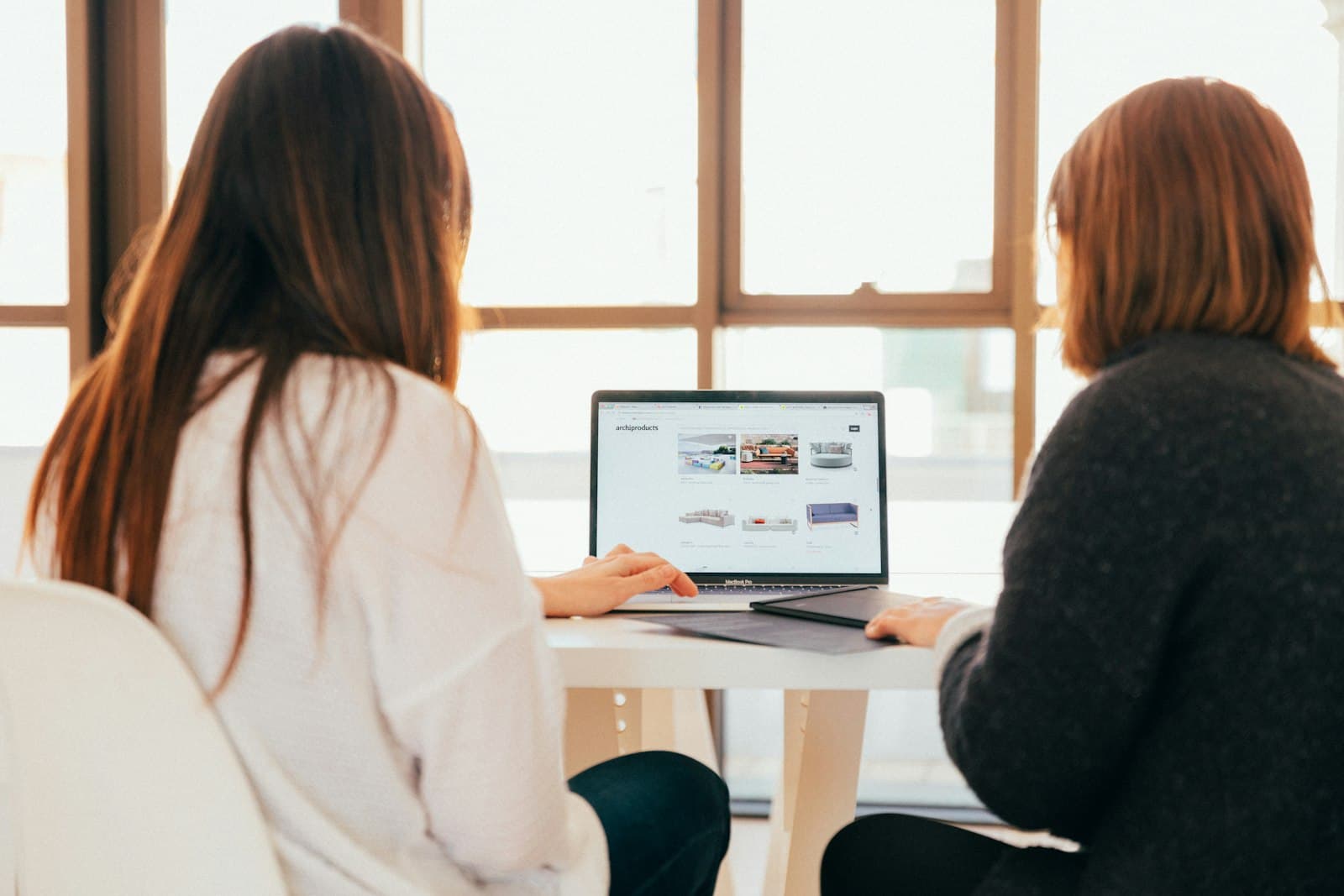 Deux collègues discutant devant un laptop dans un bureau